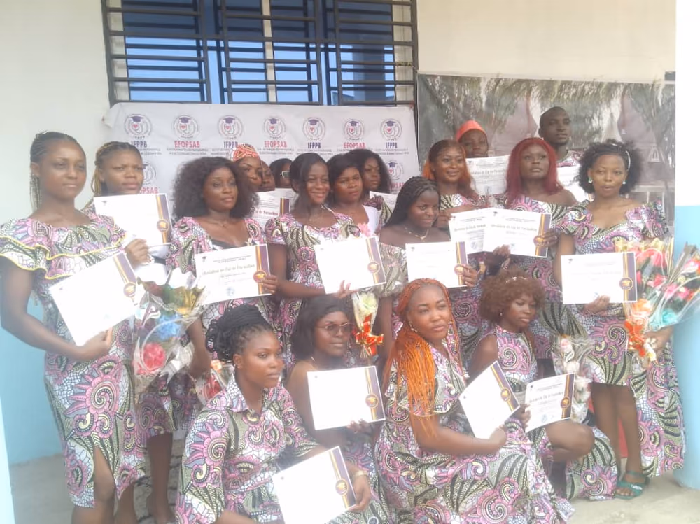 Les diplômées présentent leur attestation encadrée, bouquets à la main, devant le kakémono aux logos des deux établissements.