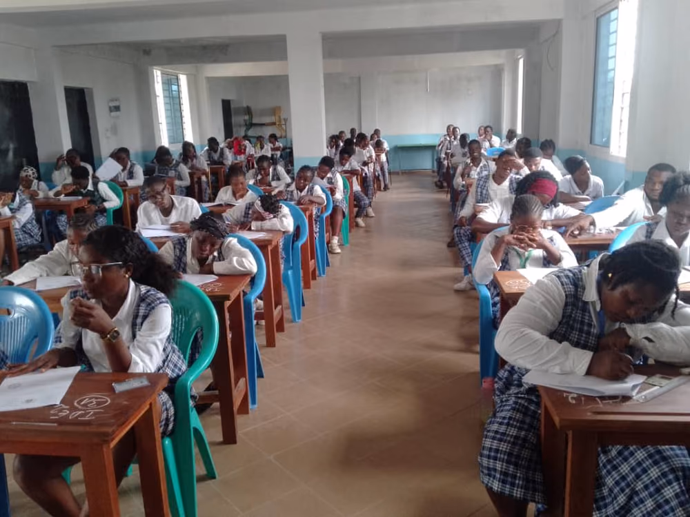 Une salle de classe de l'école, où les étudiantes en uniforme composent à des tables individuelles.